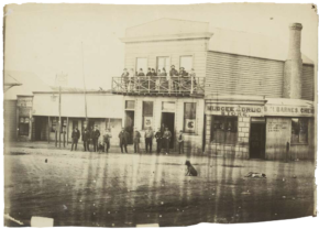 Men and women in front of Sportmans Arms Hotel, next to Barnes Mudgee Store and Plunkett and Co. auctioneers, Mayne Street, Gulgong, New South Wales, ca. 1872